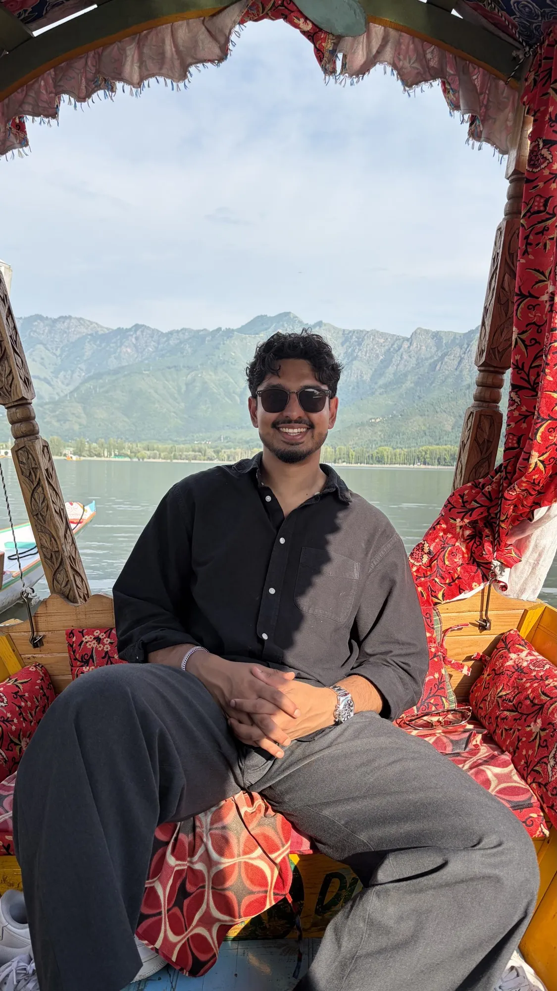 Aamir Khan sitting in a boat on a lake with mountains behind him